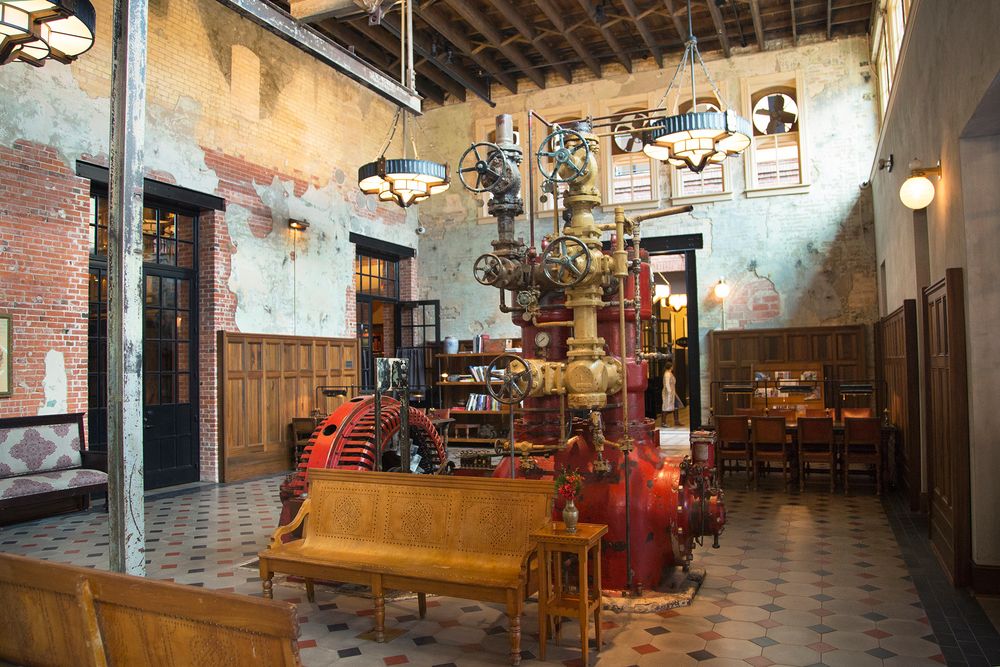 A rustic dining area in a historic tavern features exposed wooden beams, antique decor and warm lighting throughout.