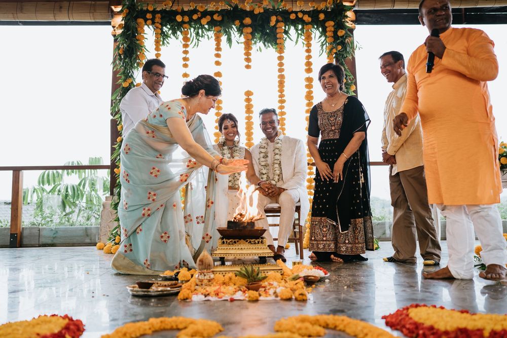 Wedding celebration with guests mingling in a decorated venue featuring orange garlands and mountain backdrop.