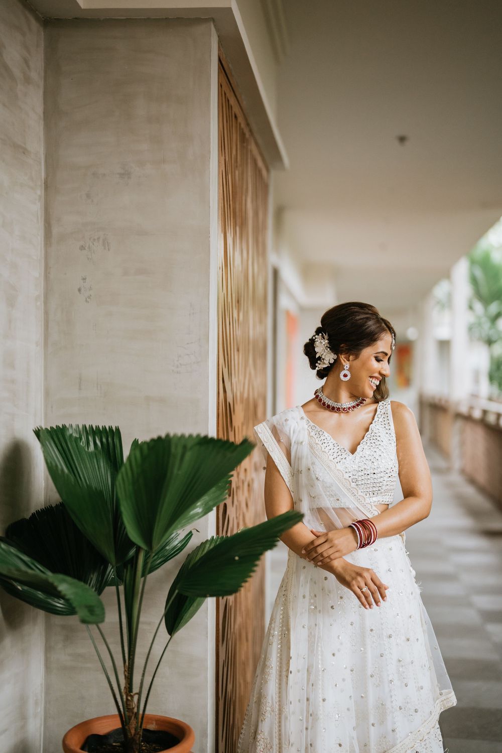 Artistic bridal portraits featuring a white lace dress and traditional Indian accessories in a columned walkway.
