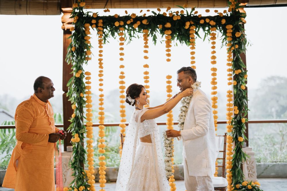 A wedding ceremony setup with orange marigold garlands and greenery decorations on an outdoor terrace.