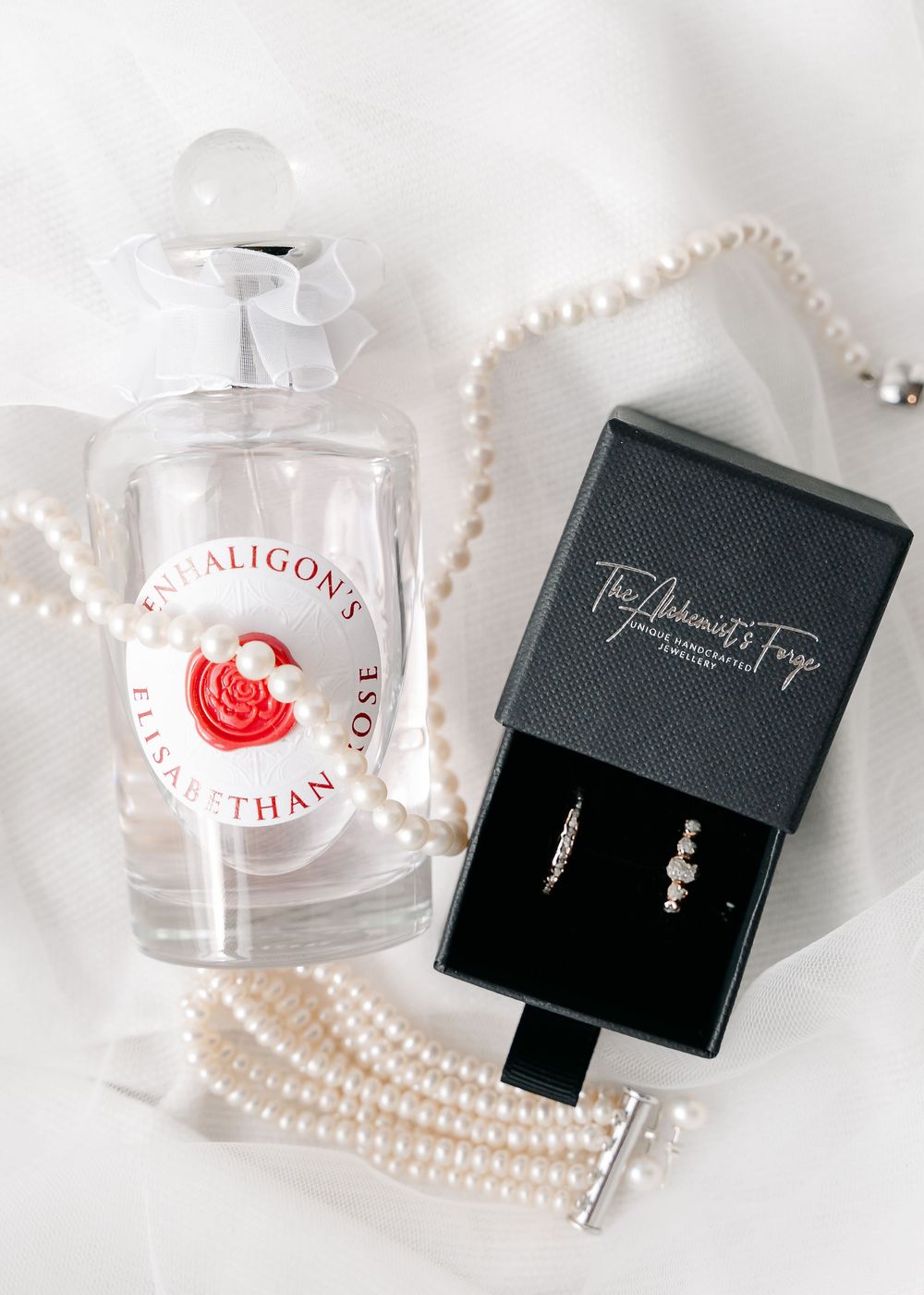 Wedding accessories including pearl necklace and jewelry boxes arranged on white background.