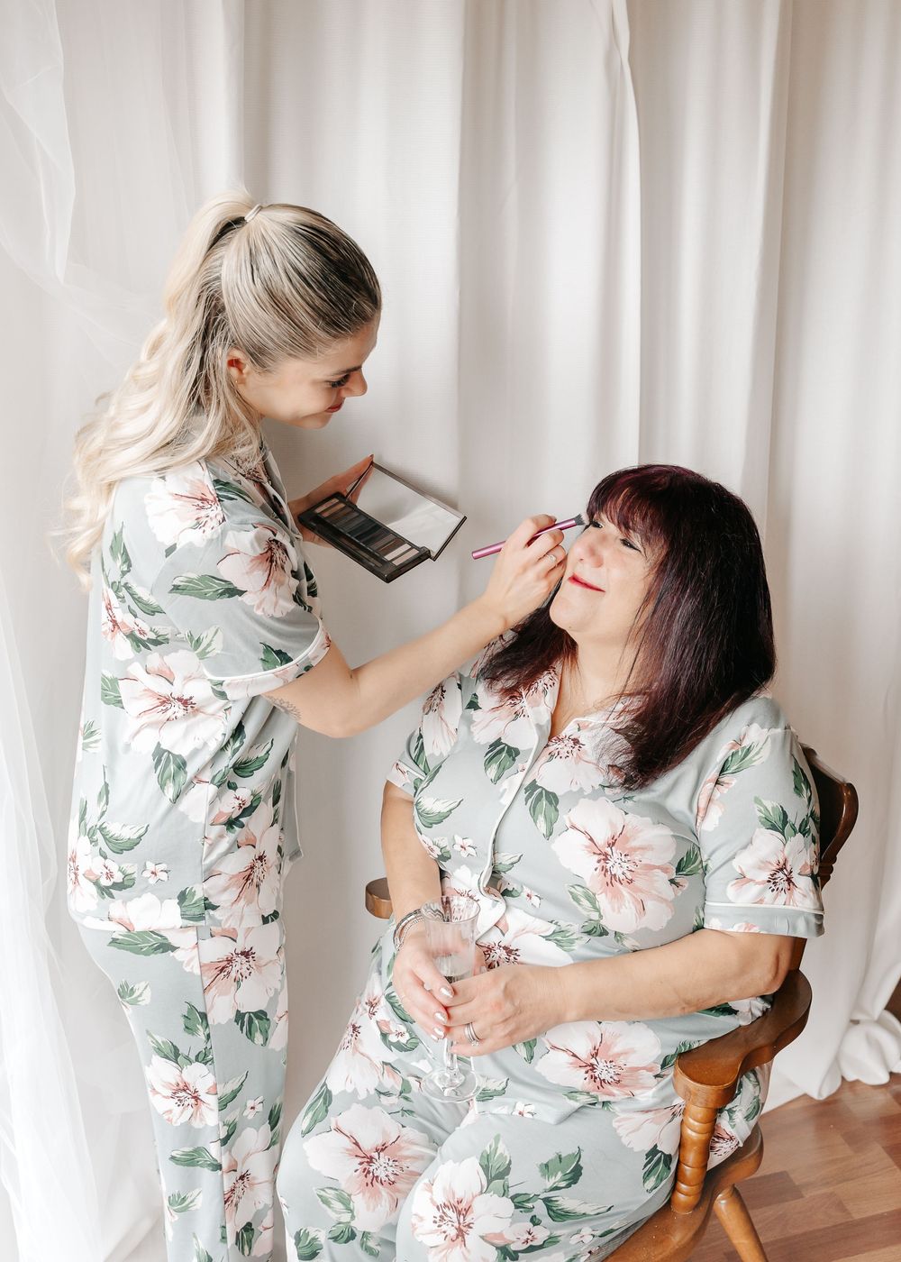 Women bond and laugh together while wearing coordinating floral and solid colored dresses.