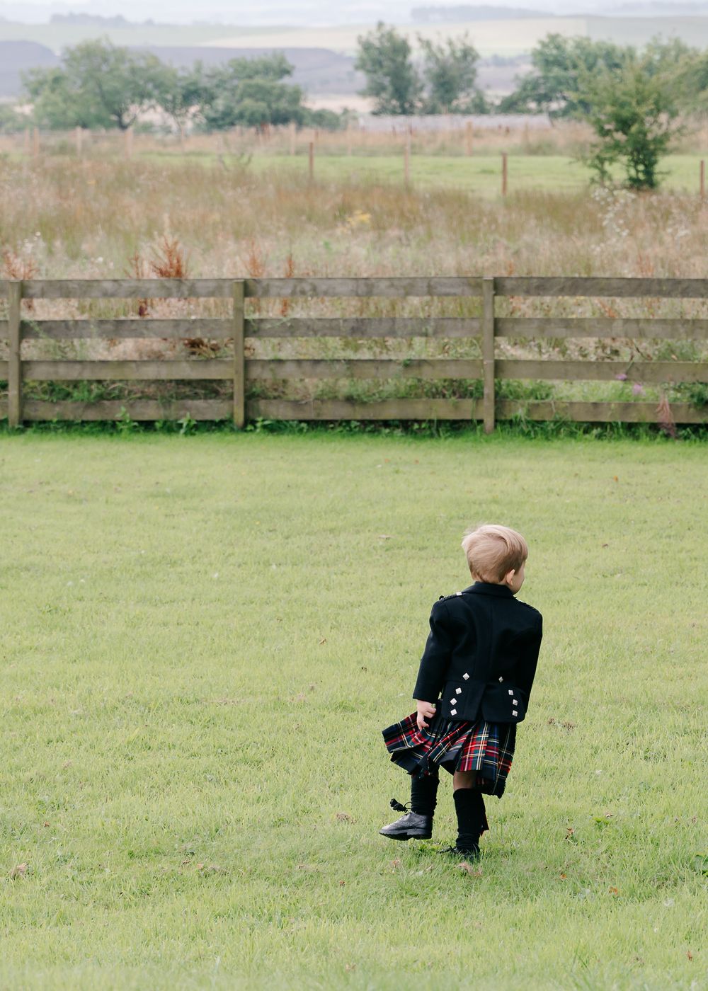 Series of playful moments captured as children in formal wear explore a grassy field.