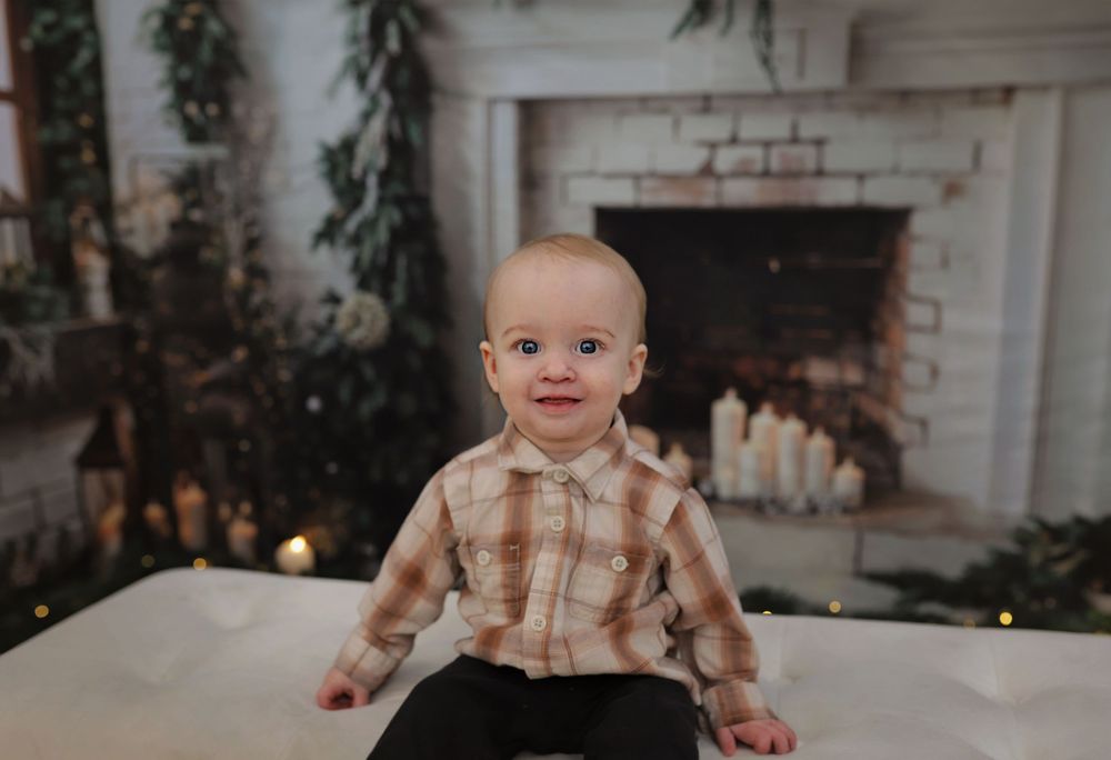 Holiday family photoshoot in front of white brick fireplace with festive greenery and twinkling lights.