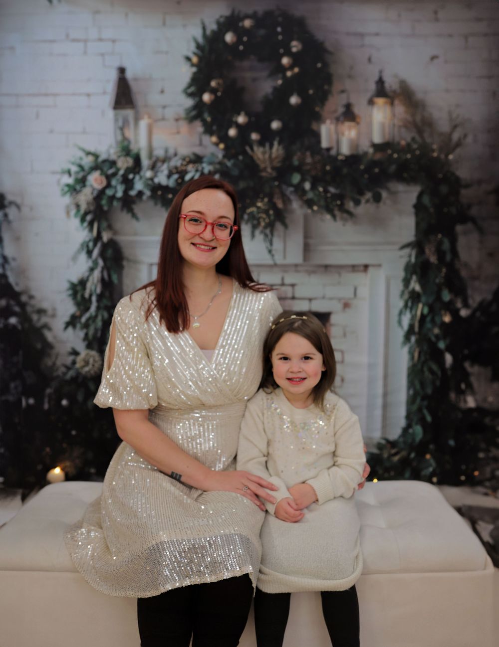Intimate holiday portraits on white couch with sparkly sequin and cream colored outfits.
