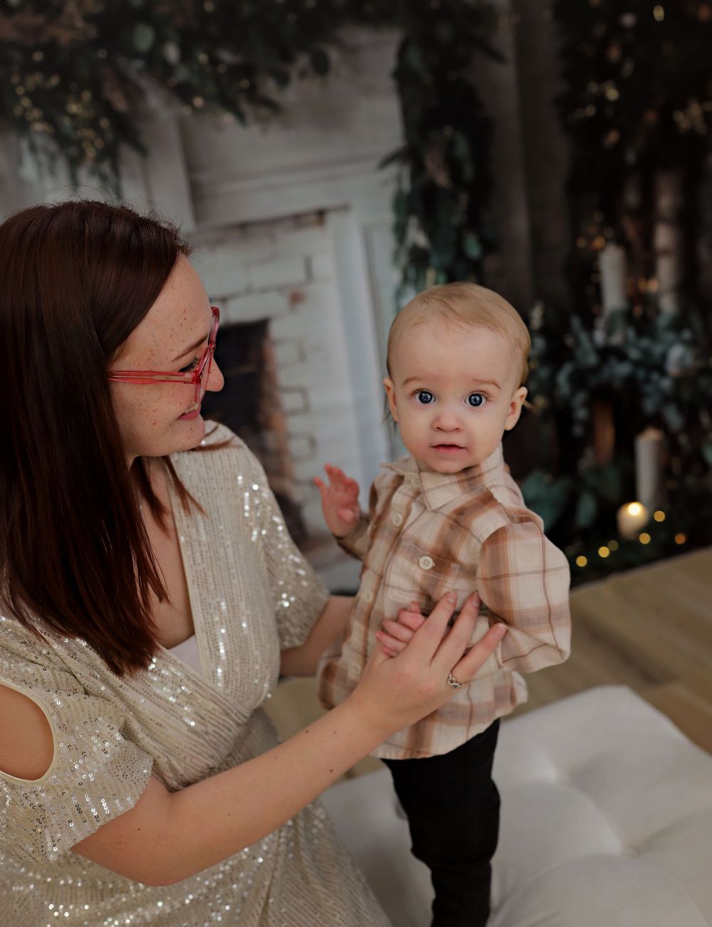 Sweet holiday photo session with plaid and sparkly outfits against festive backdrop.