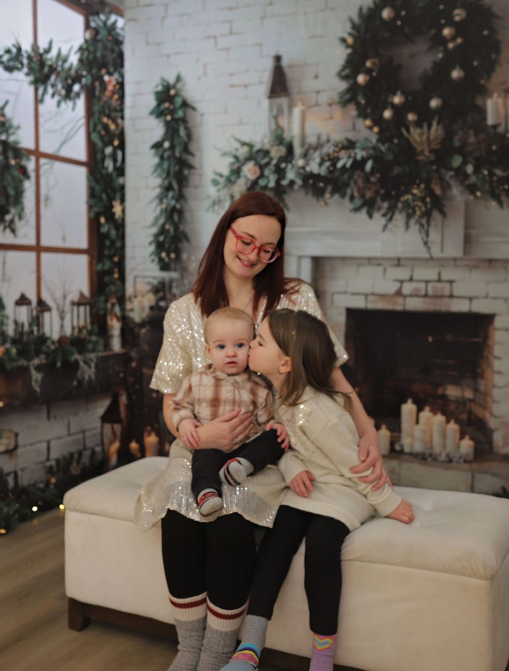 Tender family moments during Christmas photoshoot with white brick fireplace.