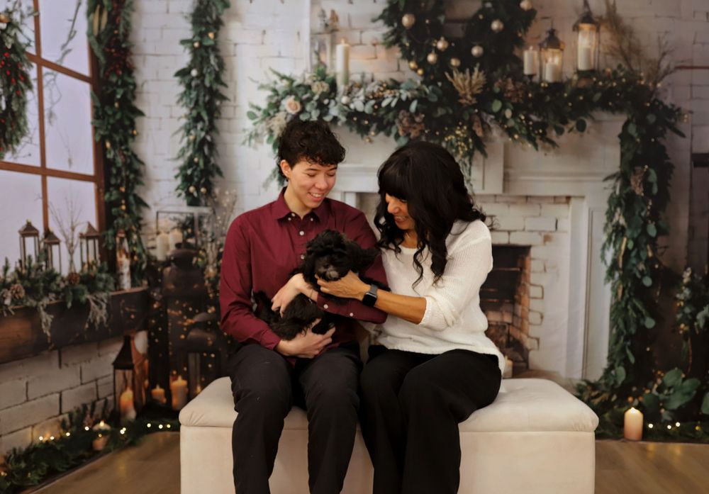 Studio photography setup with holiday decorations and white brick fireplace backdrop.