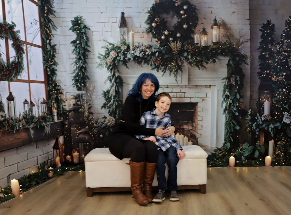 People posing in a cozy holiday setting with white brick fireplace and evergreen decorations.
