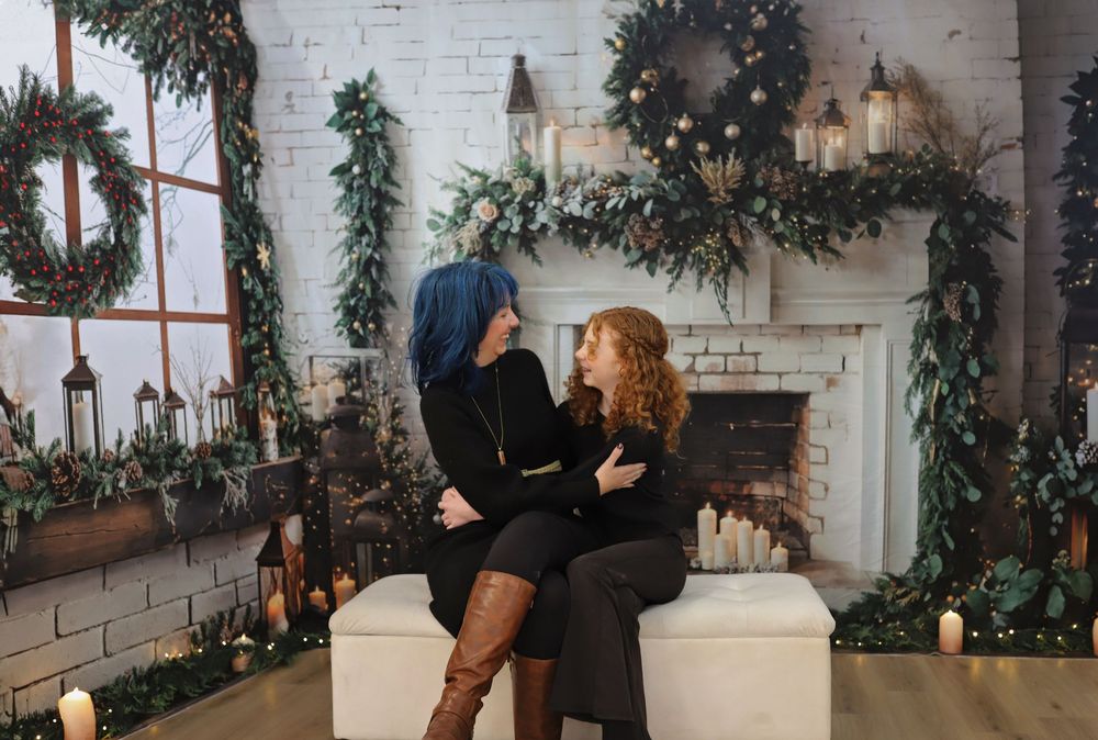 Winter portrait session with elegant holiday decorations and white brick fireplace.