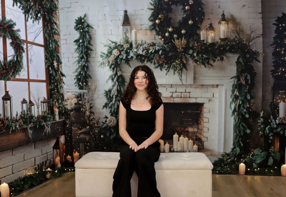 Holiday photoshoot featuring elegant decor and white brick fireplace background.