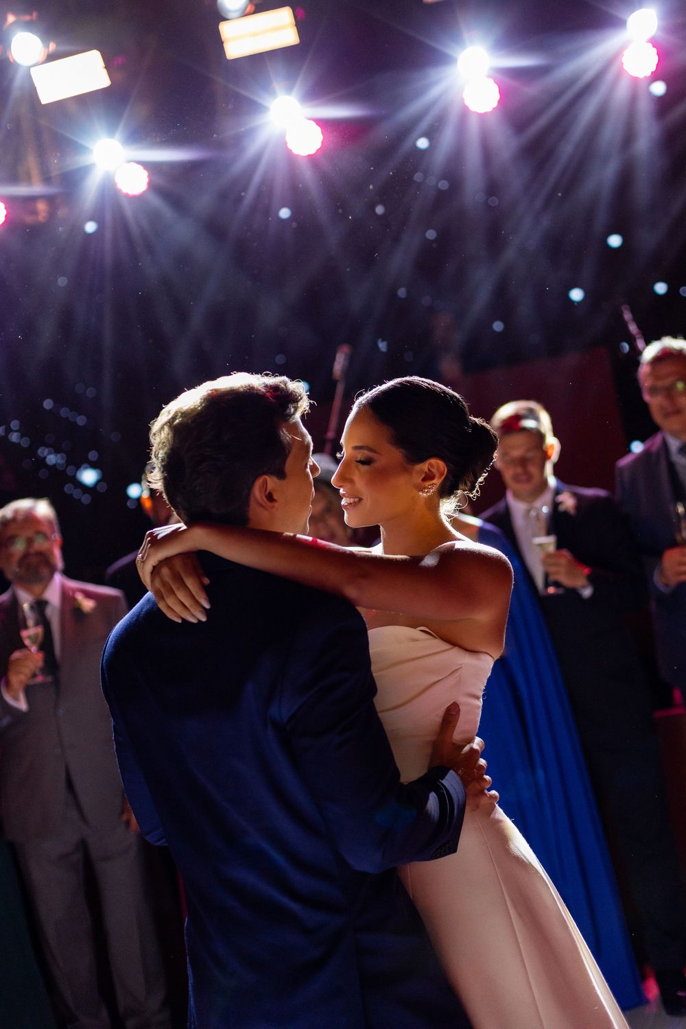 Couple shares an intimate first dance moment under dramatic stage lighting at their wedding reception.