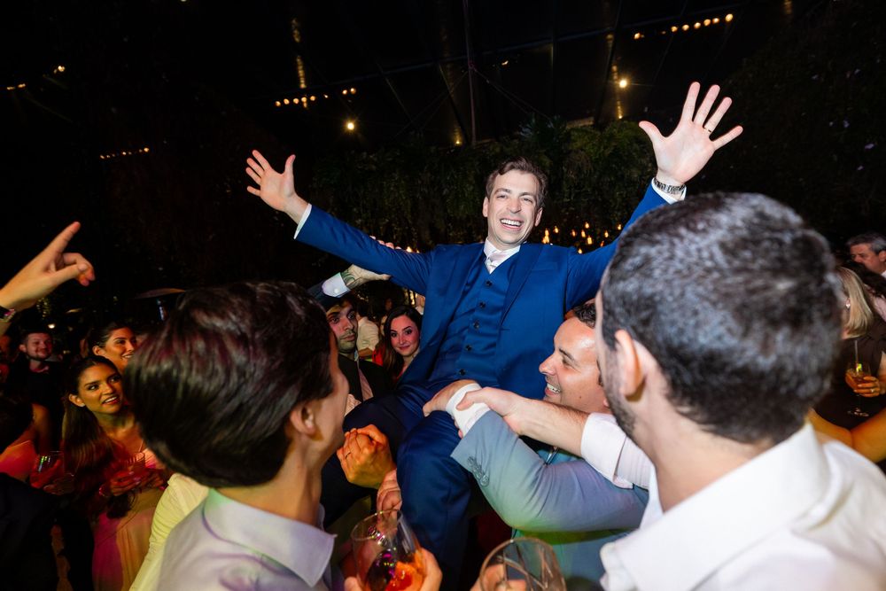 Wedding guests dance and celebrate enthusiastically on a crowded dance floor at an evening reception party.