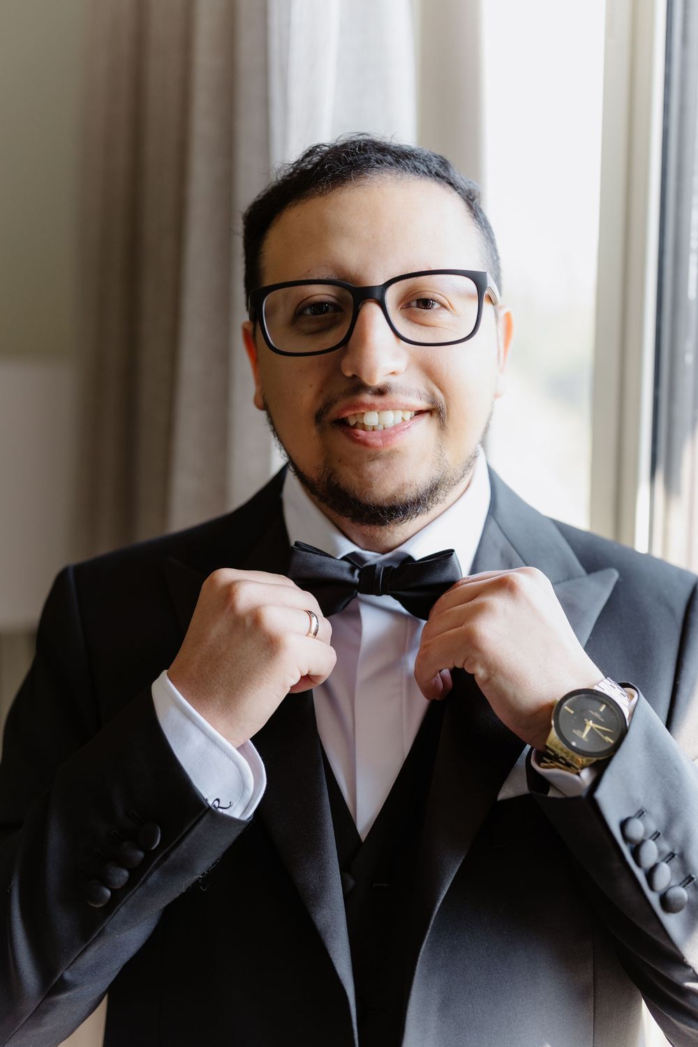 Collage of someone adjusting their black bow tie while wearing a formal dark suit and glasses.