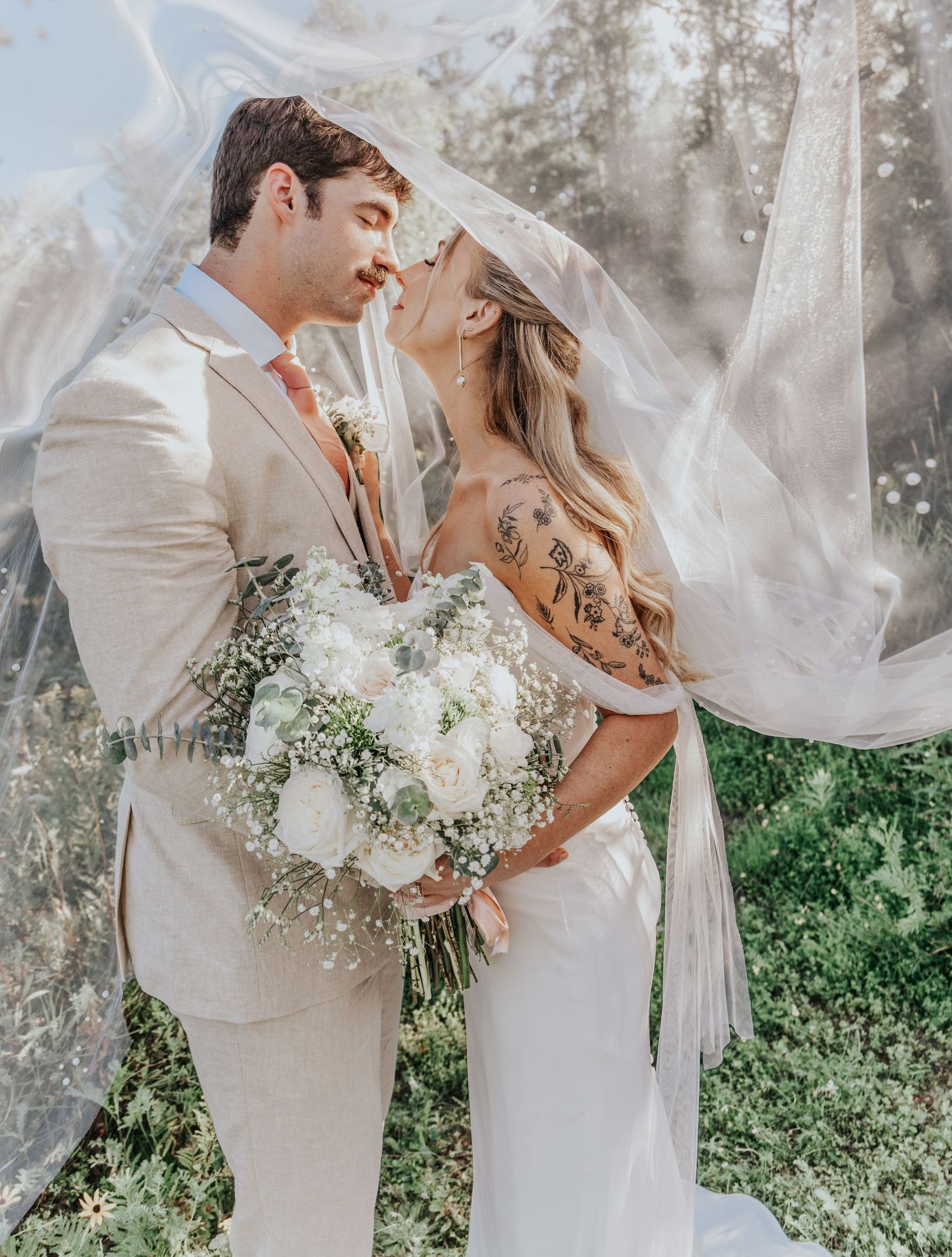 A romantic wedding photo with a flowing veil and white floral bouquet in a dreamy forest setting. Duluth, MN