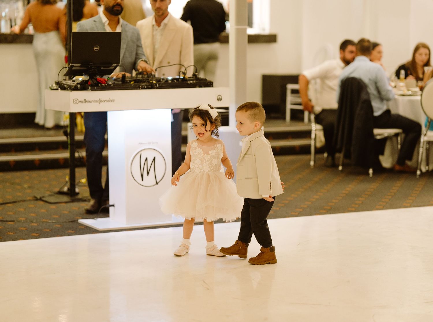 Wedding guests dance together on a wooden dance floor during an elegant reception celebration.