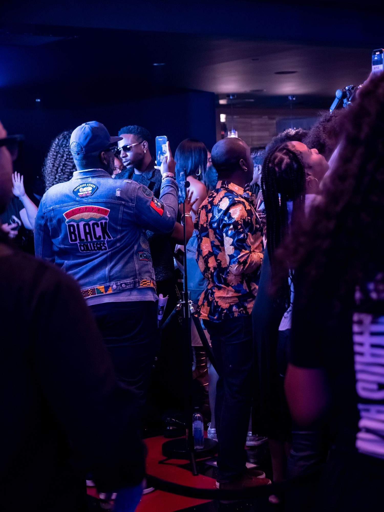 Crowd mingles at a nightclub-style event with blue lighting and Netflix signage.