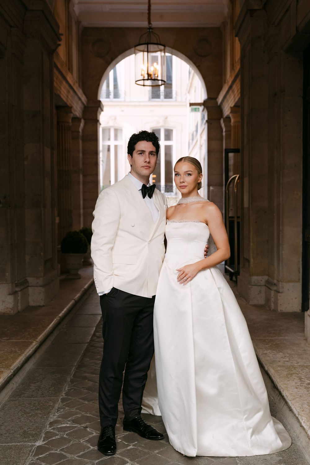 A wedding couple poses in a series of romantic shots under an elegant archway in a historic building.
