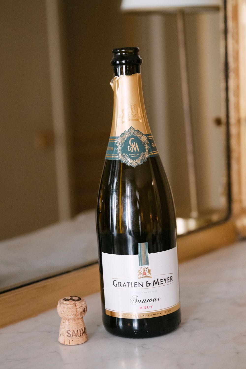 A series of champagne bottles with cork closures arranged in a row on a white marble surface.