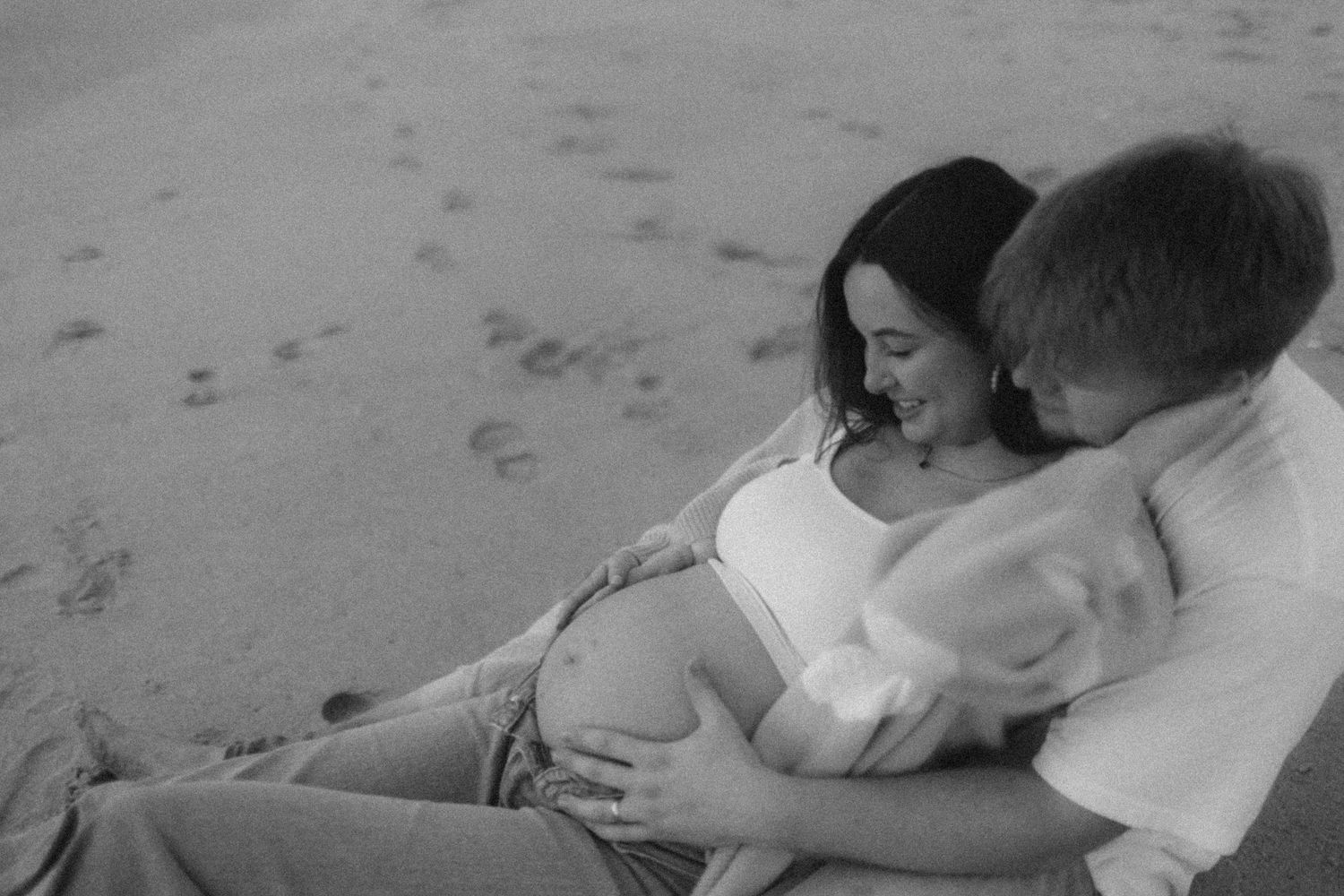 Black and white photos of tender moments shared on sandy beach. Maternity on the space coast in Florida at sunrise.