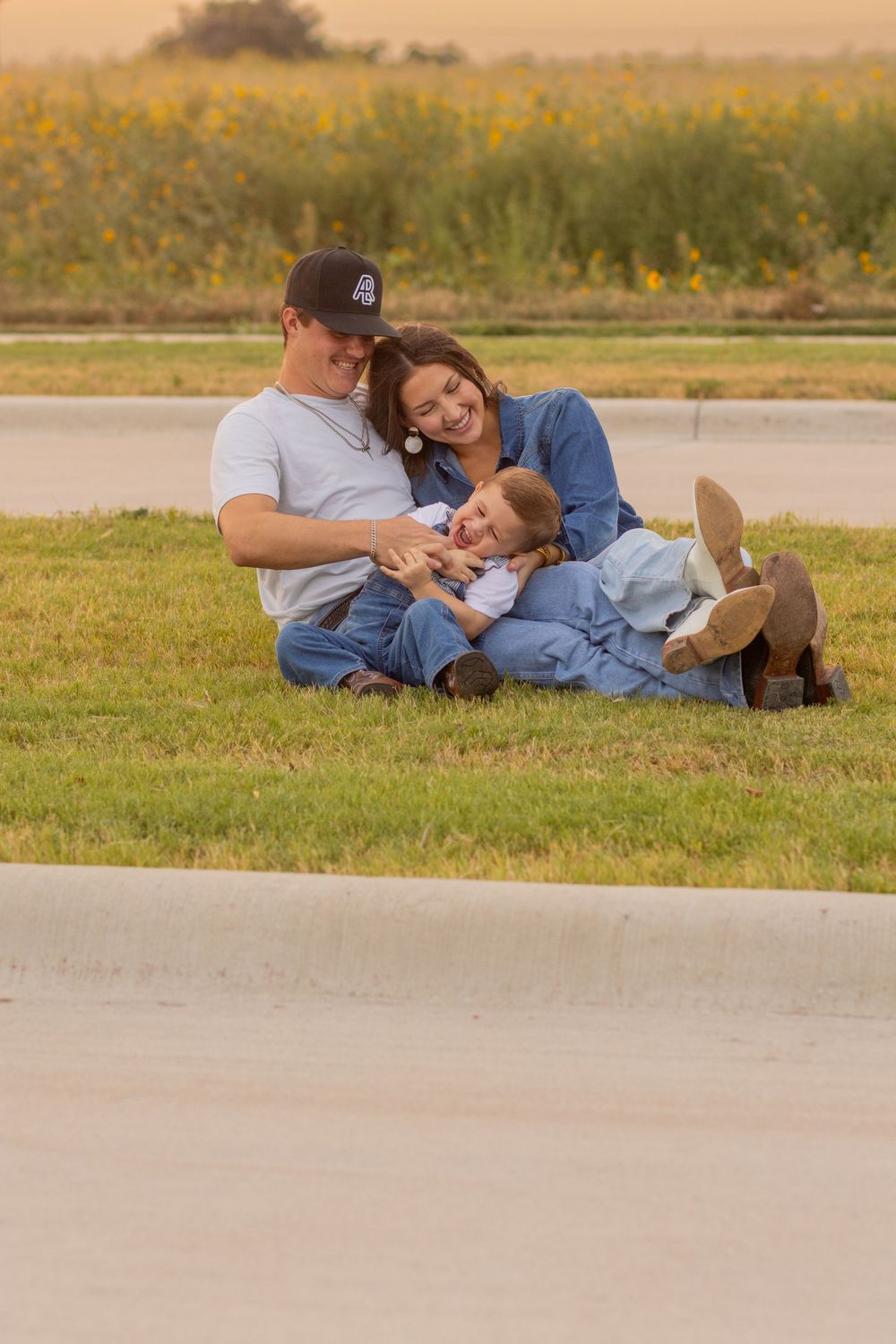 Family relaxing together on grass during golden hour sunset.