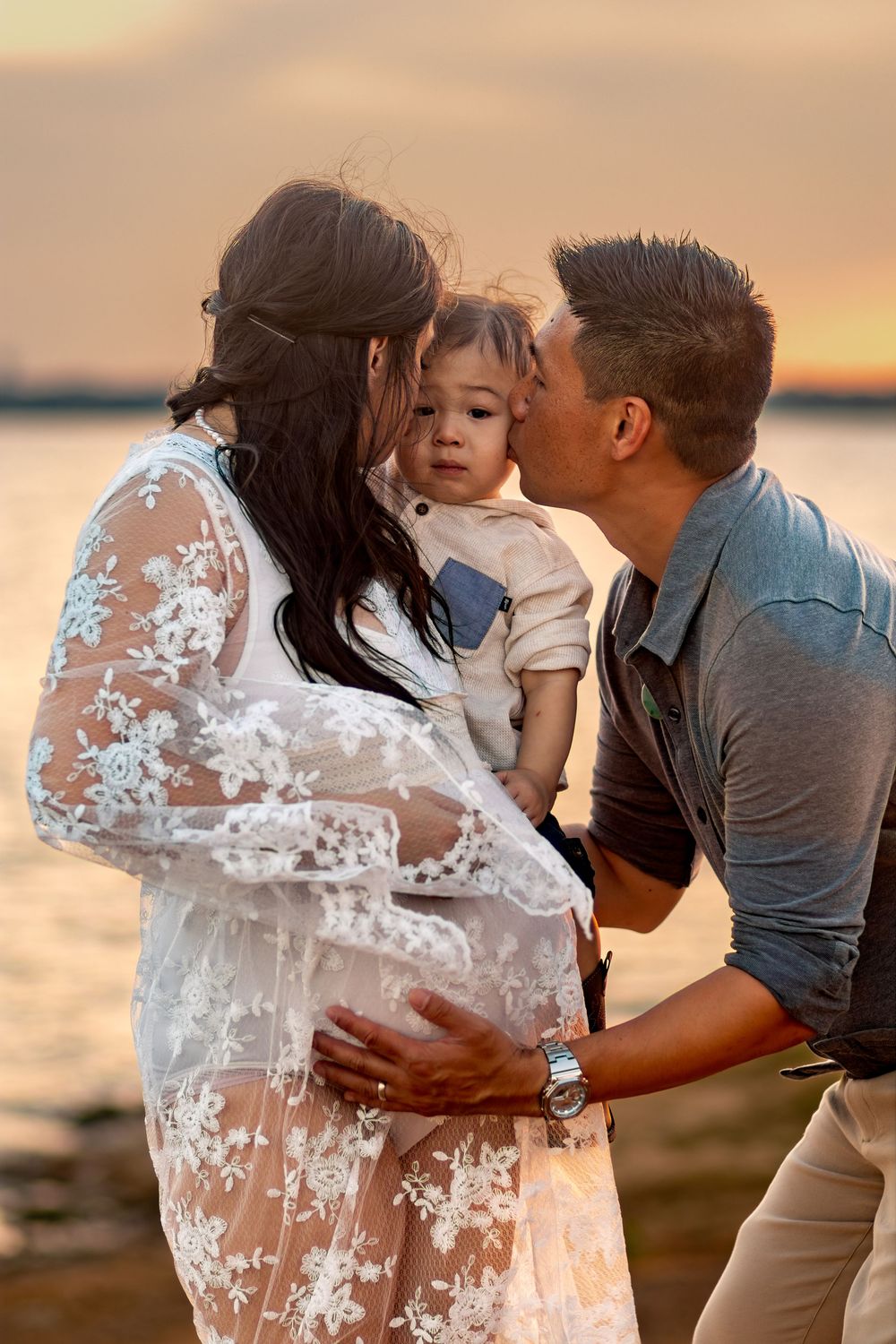 Family sharing tender moments together at sunset by the water.