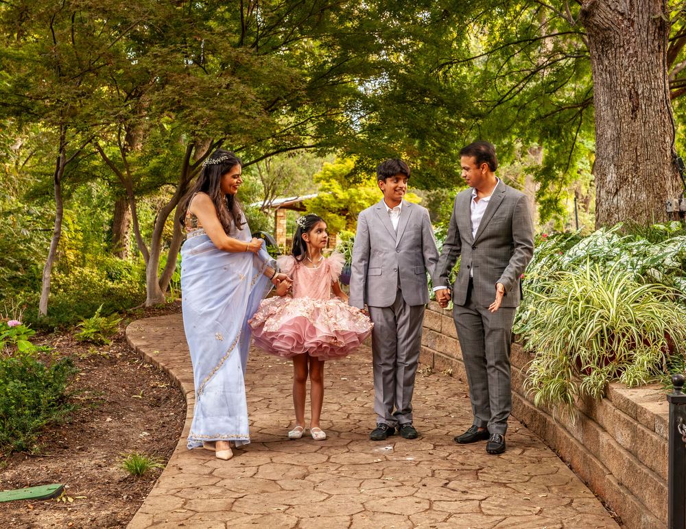 Wedding party walks along tree-lined garden path during outdoor ceremony.