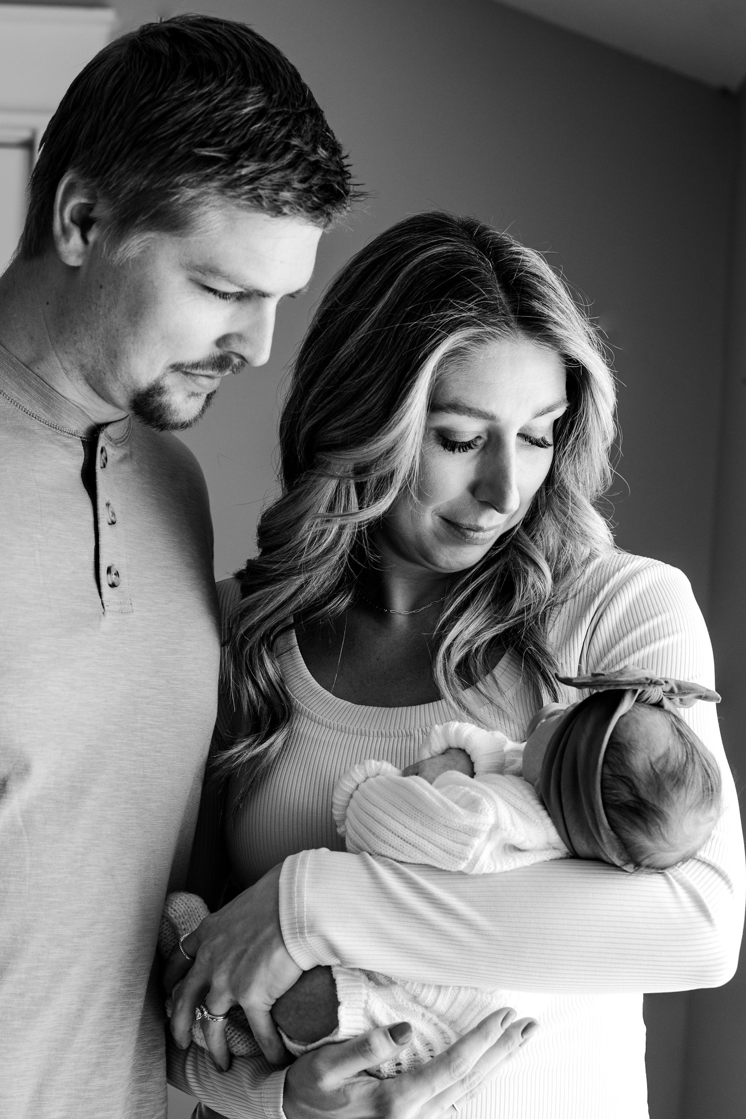 Black and white photo series showing tender moments between parents and newborn baby.