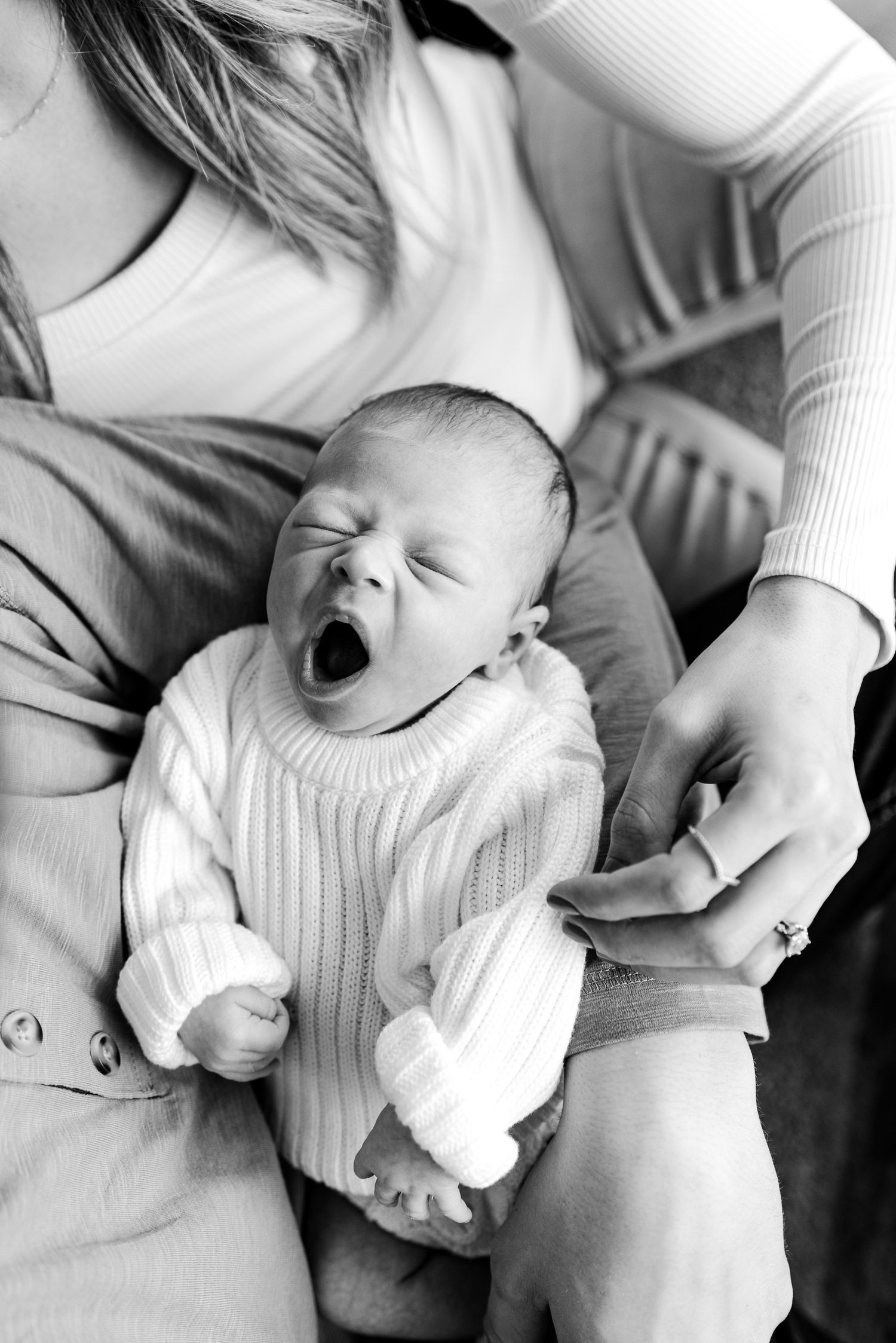 Black and white candid photos capturing playful moments between parents and their infant.