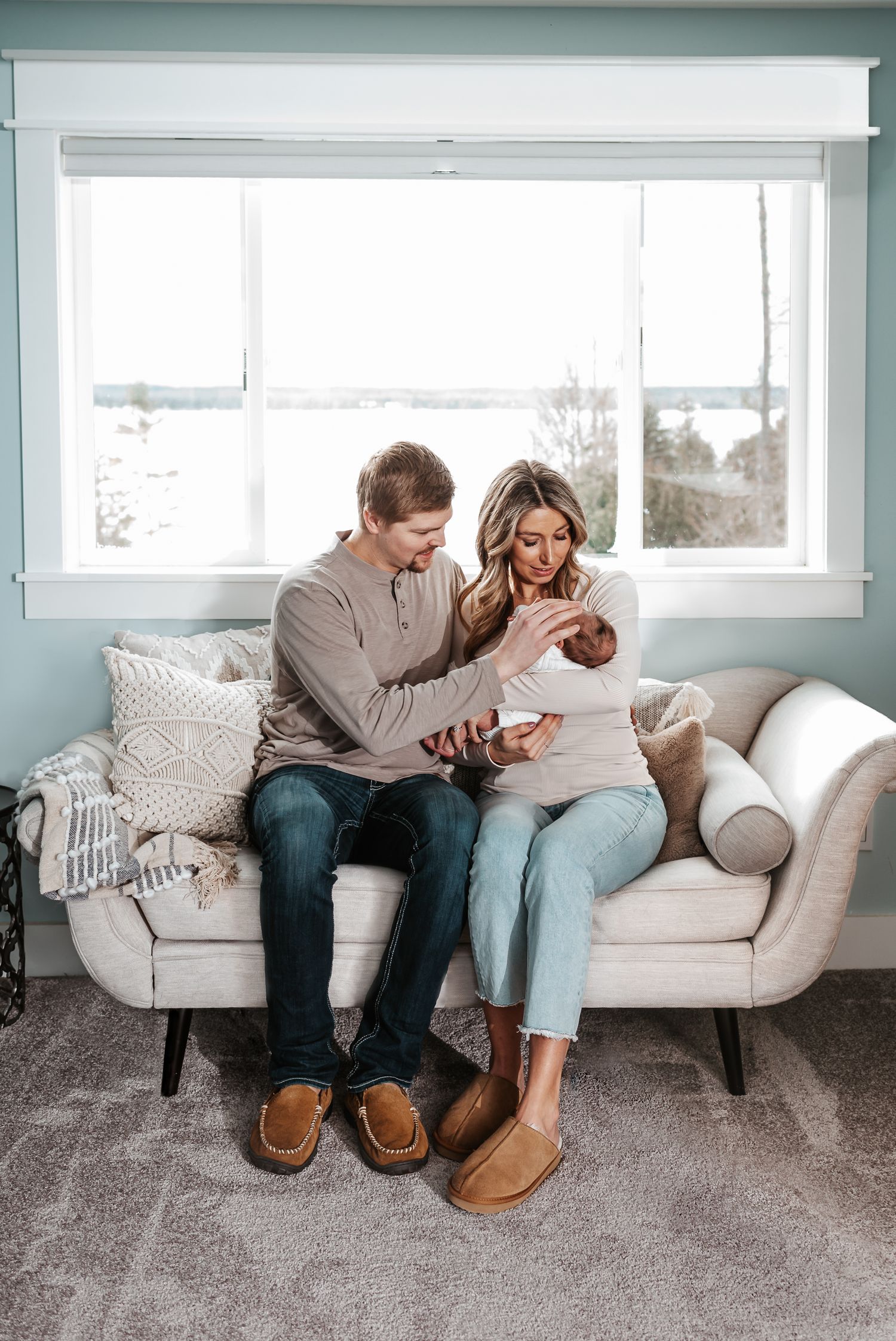 Couple relaxing together on a cozy white couch wearing matching cozy slippers.