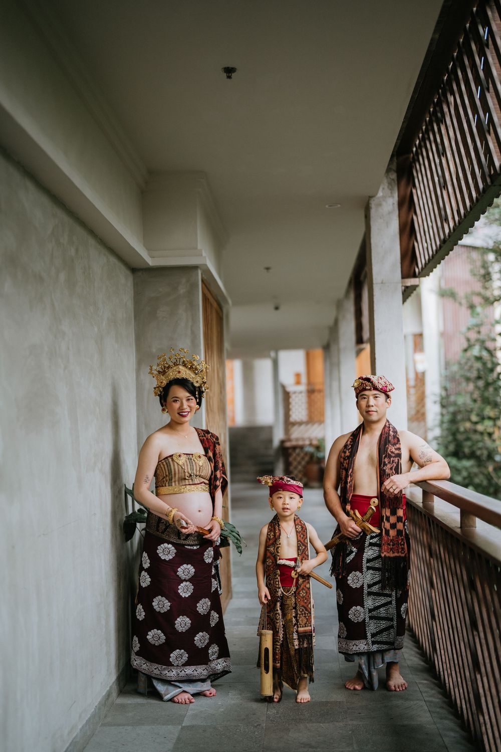 People in traditional Indonesian dress standing in a white corridor with columns.