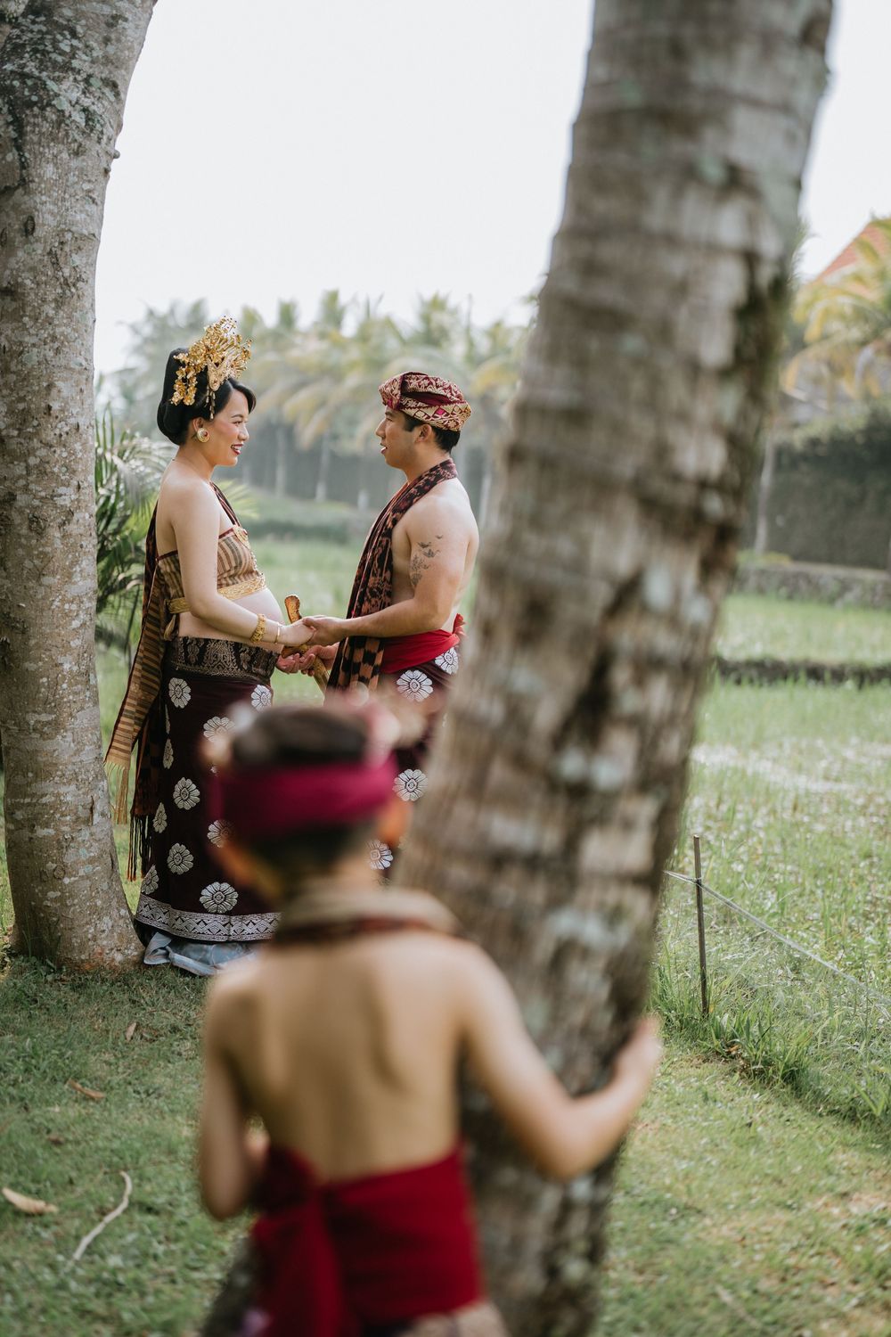 Candid moments captured between two people in traditional dress among palm trees in a garden setting.