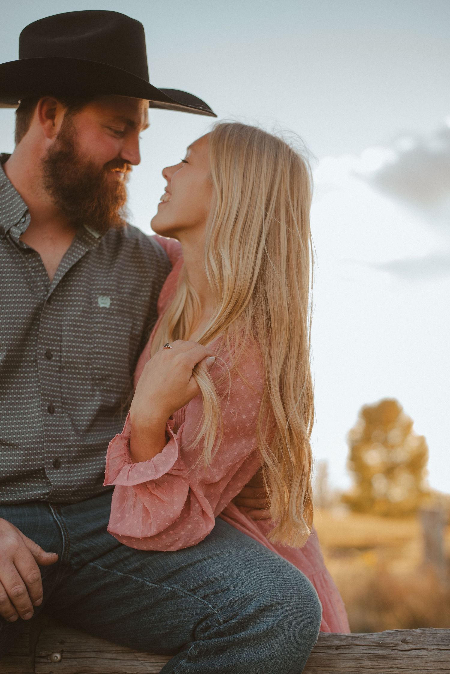 Romantic couple in casual western wear sharing intimate moments during sunset photo session.
