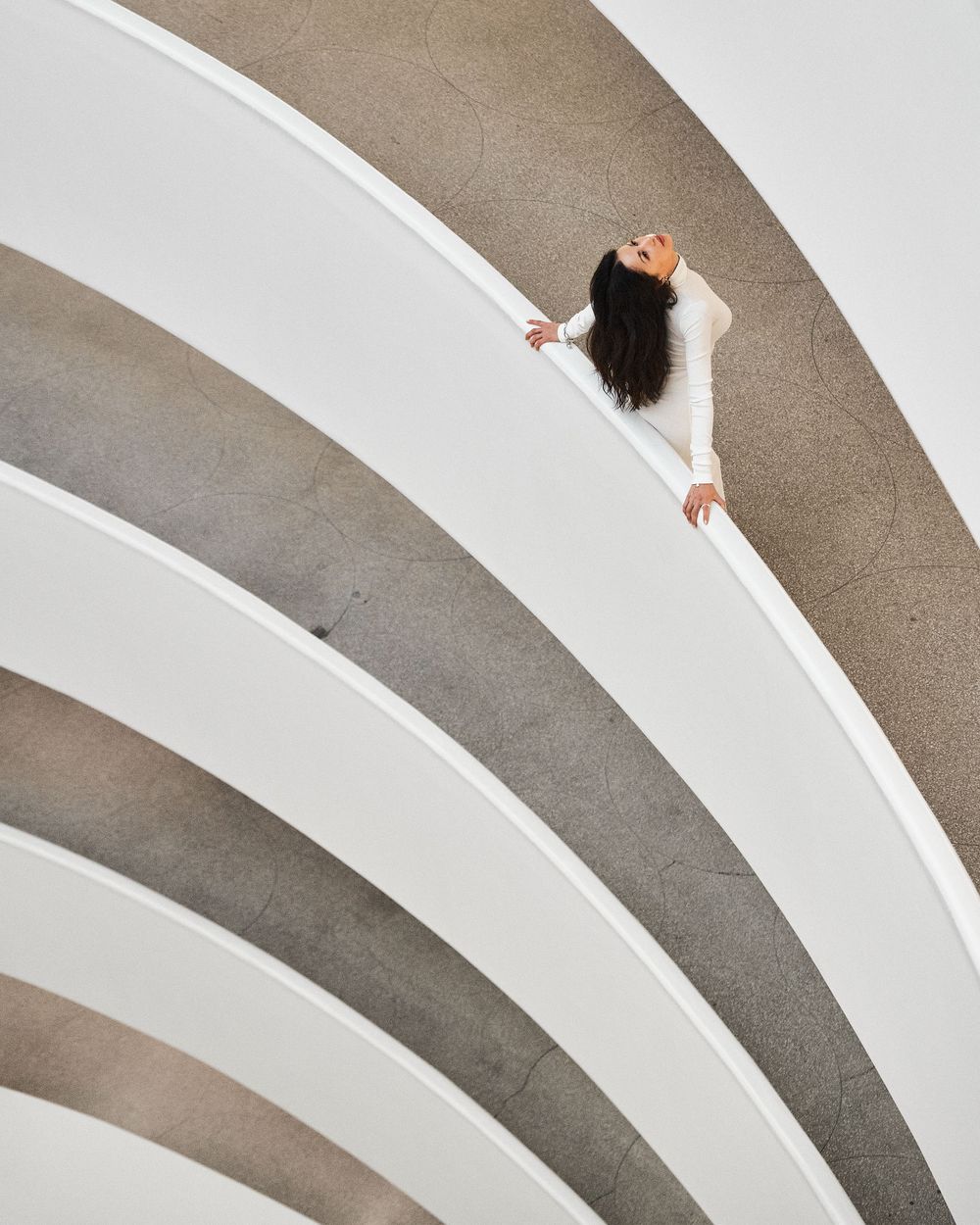 Abstract architectural detail of white curved concrete balconies against a beige wall creating a geometric pattern.