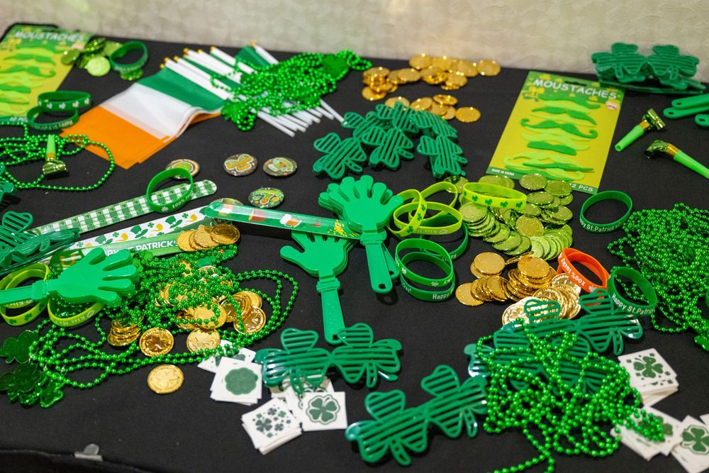 Various green Irish St. Patrick's Day party decorations and accessories arranged on a dark surface with necklaces and coins.