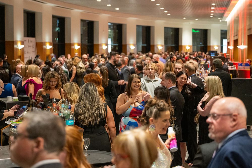 A large crowd of business professionals gathered in a modern conference venue during a corporate event.