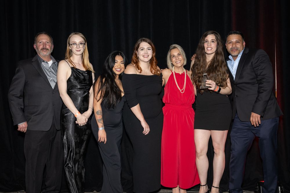 A group of people dressed in formal black and red attire pose together at an evening event.