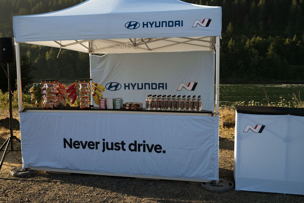 Rows of white Hyundai promotional tents and banners set up at an outdoor event with fall foliage in the background.