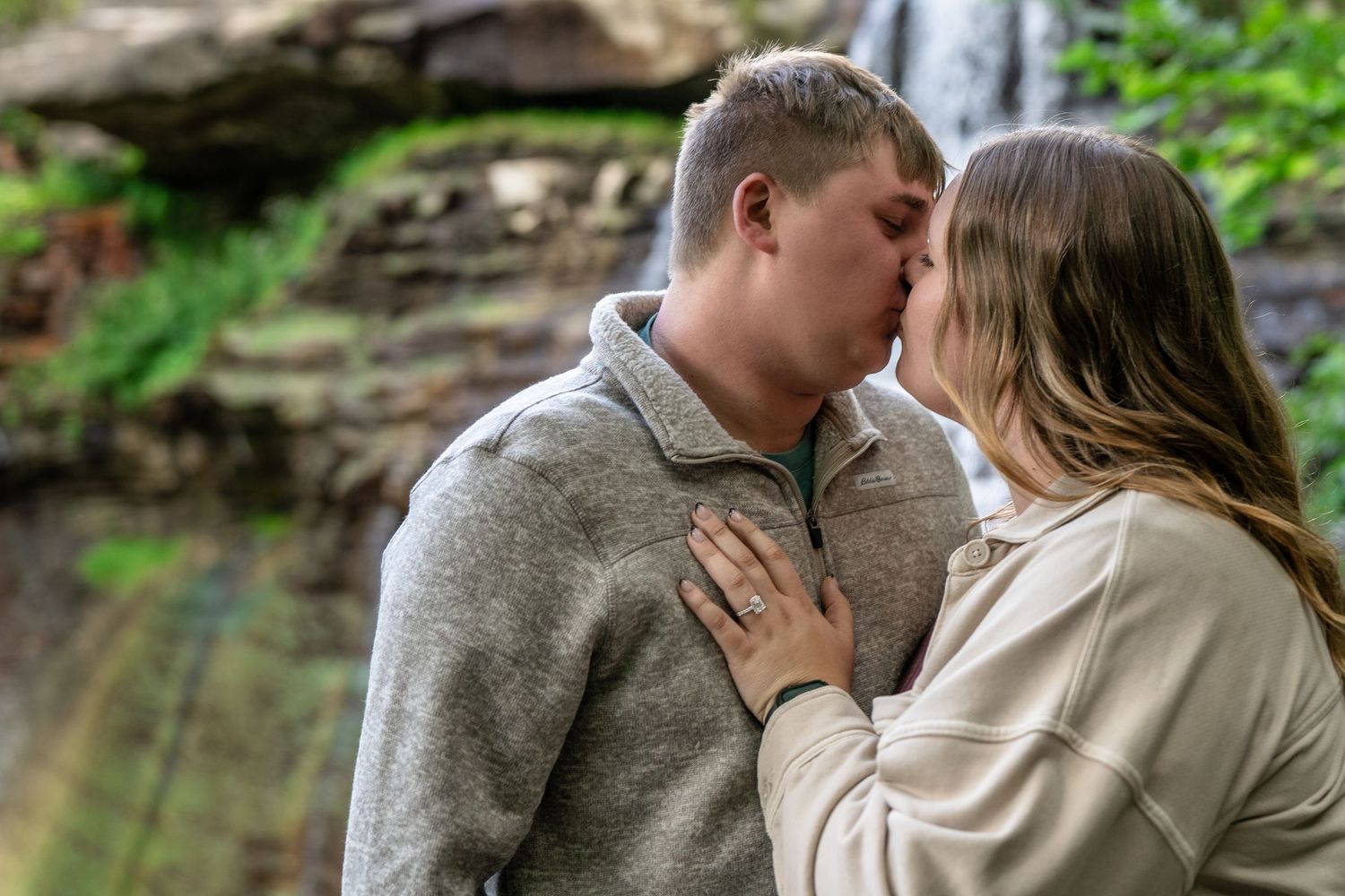 A romantic moment shared between a couple during an outdoor photo session at Brandywine Falls in Ohio for surprise engagement session