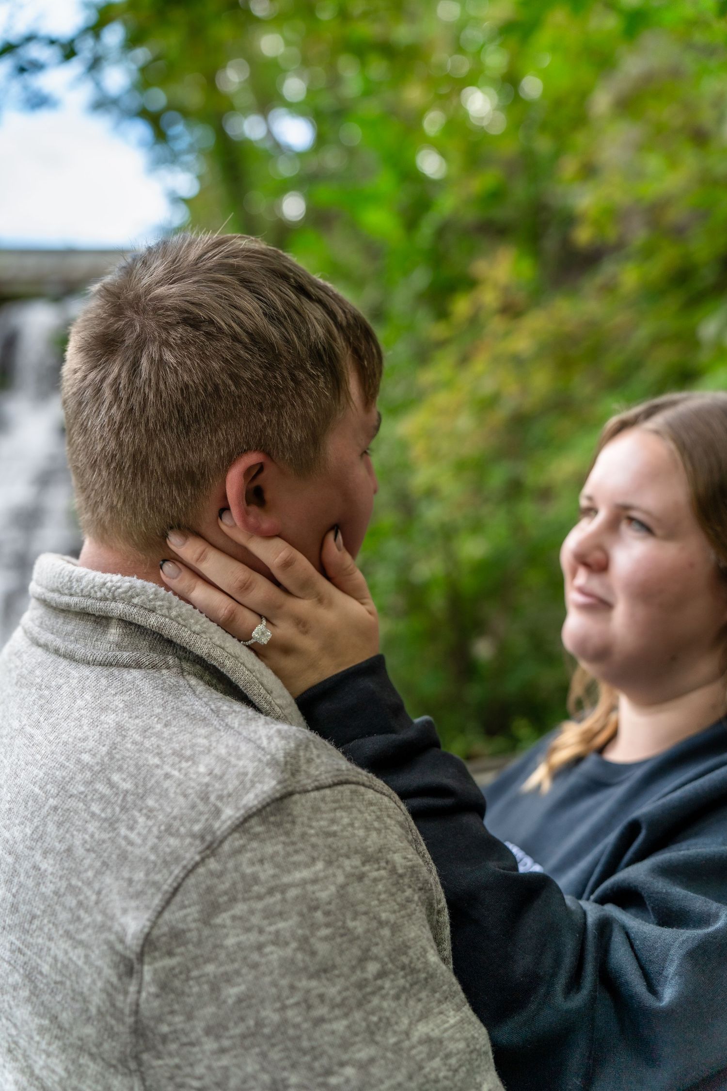 Intimate moment captured between couple during outdoor engagement photo session at Brandywine Falls in Ohio