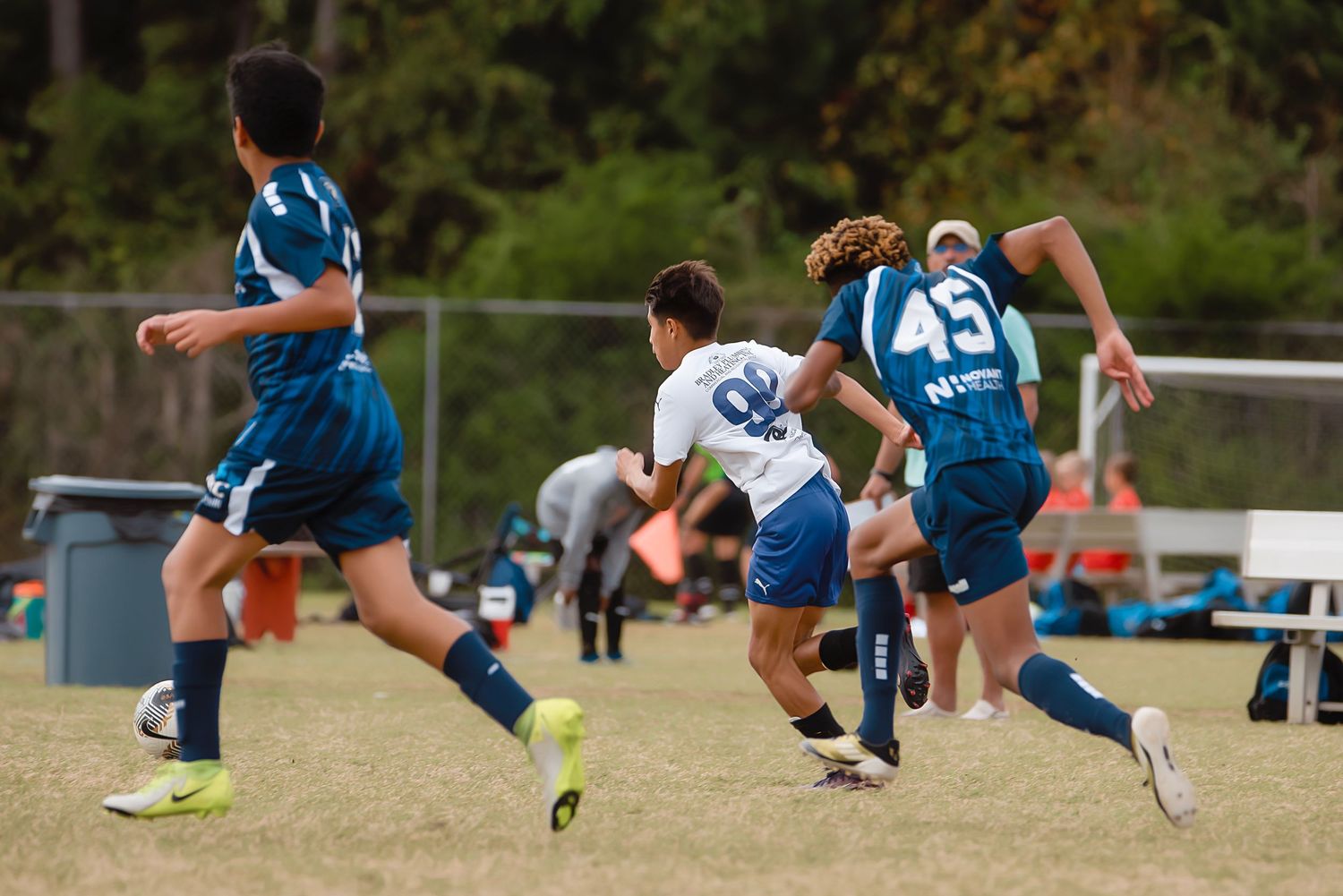 Athletes perform dynamic stretching exercises in a row on an outdoor field during warmup drills.