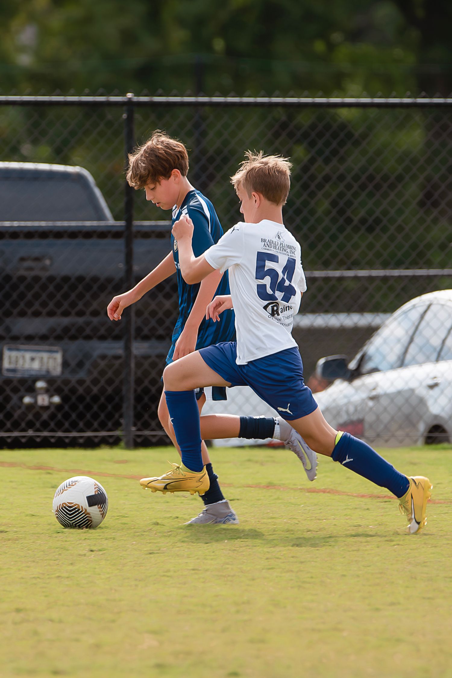 A soccer player in blue and white uniform falls during a sequence of motion shots on a grass field.