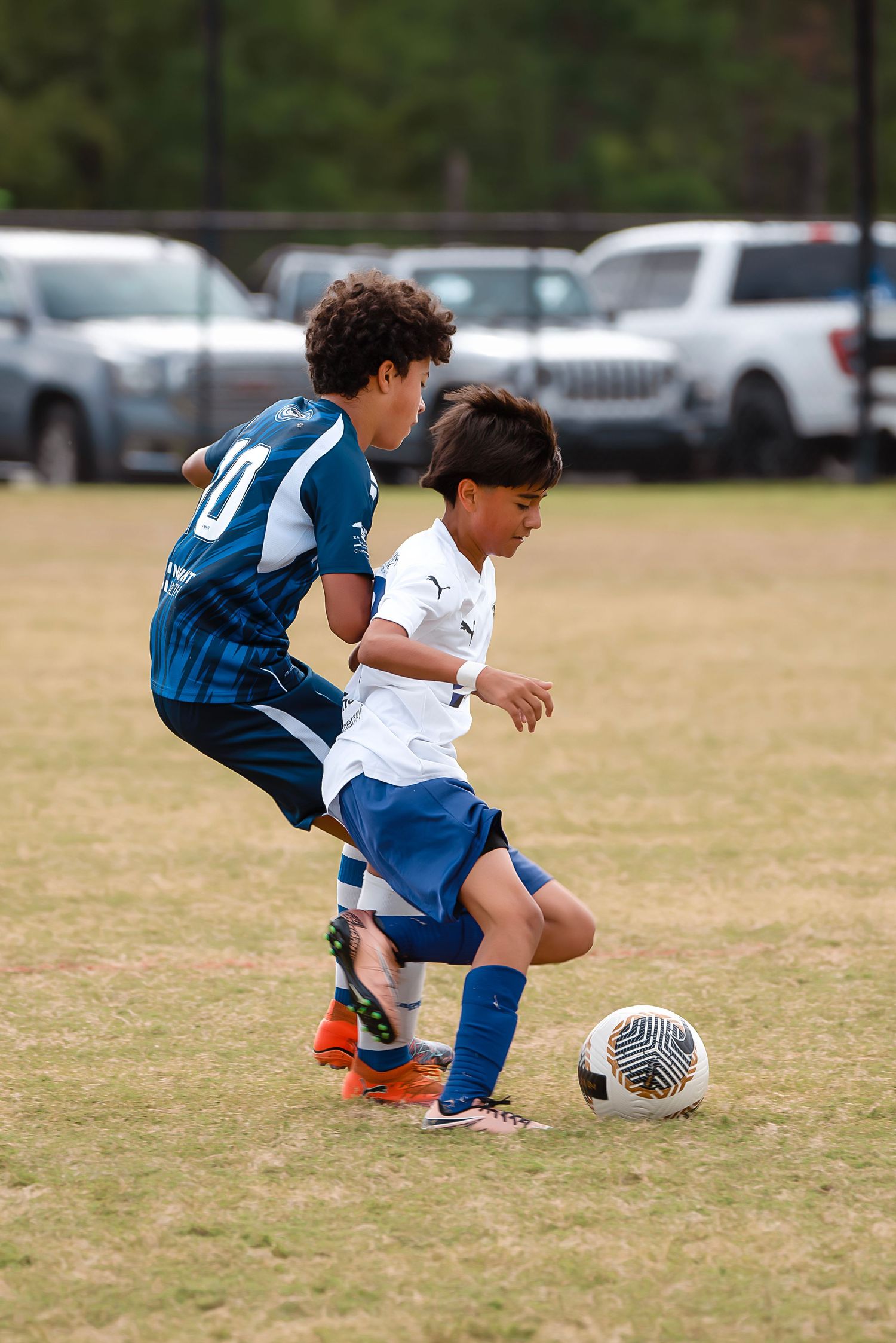 Soccer players compete for the ball in a low sliding tackle during a match.