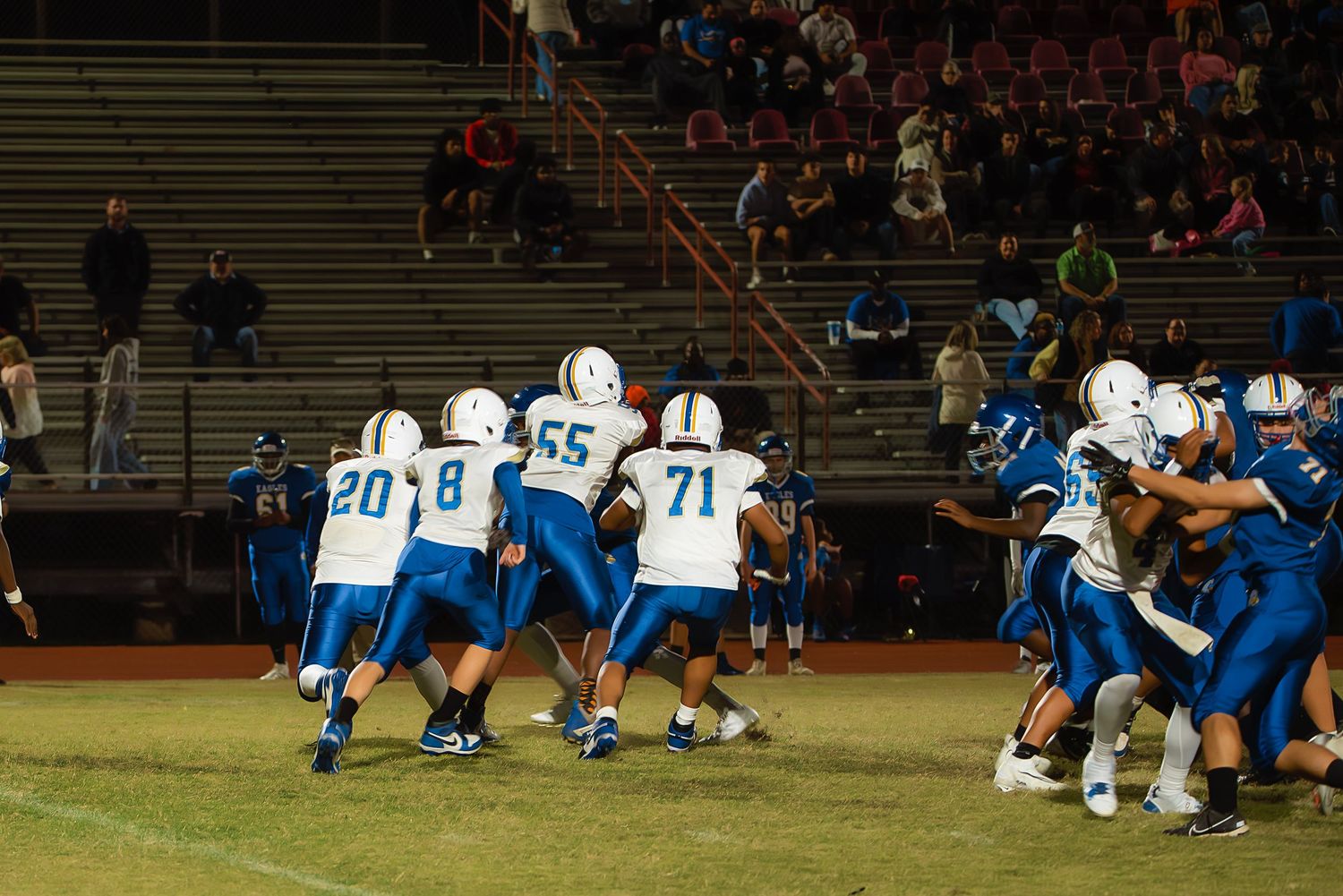 Football players in blue and white uniforms compete during an intense game play on the field.