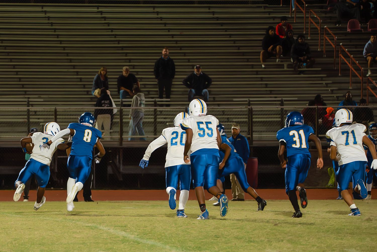 Football players stretch and warm up on a grass field before a game in their blue and white uniforms.