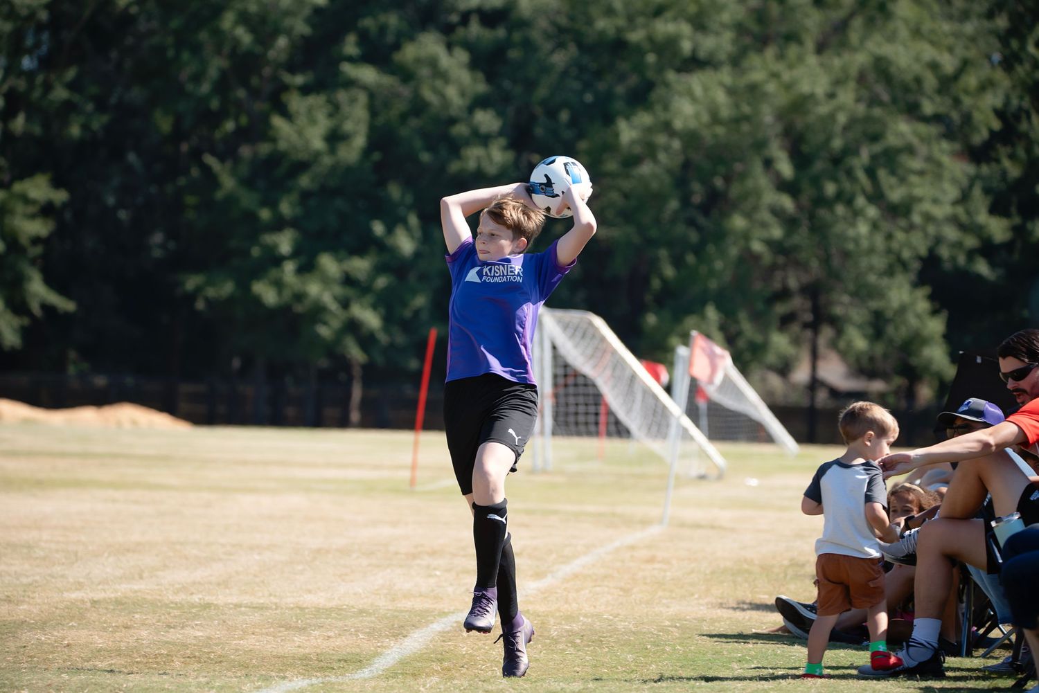 Youth soccer players compete for the ball during an intense match on a sunny grass field.