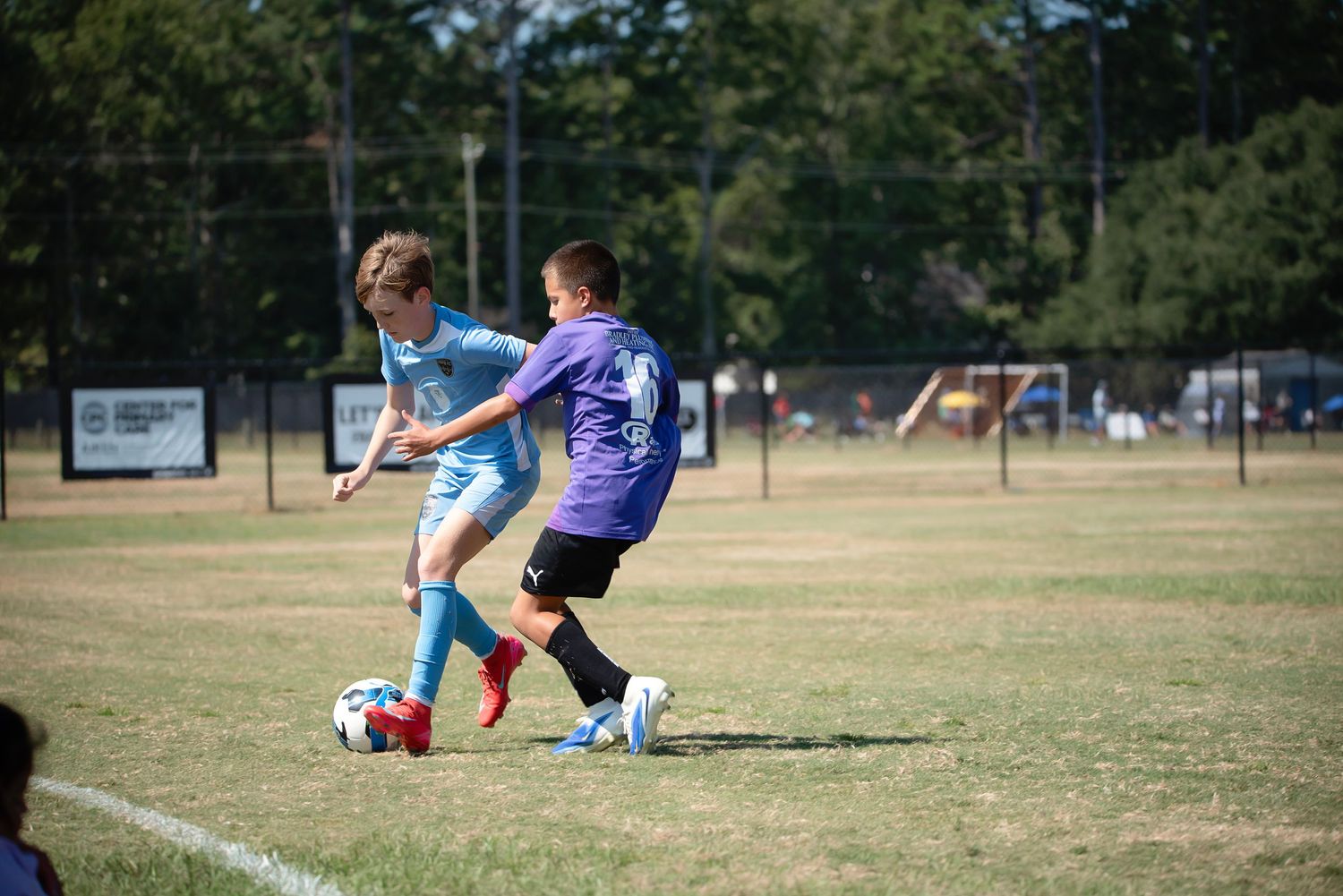 Soccer players battle for possession during a competitive match on a grassy playing field.