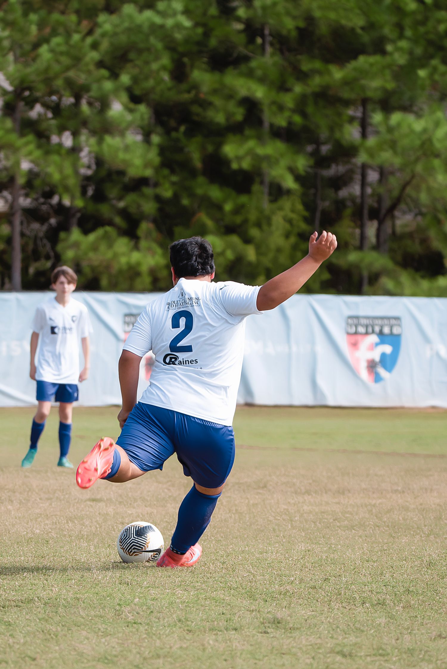 Soccer player in blue and white uniform performs an acrobatic kick on grass field.