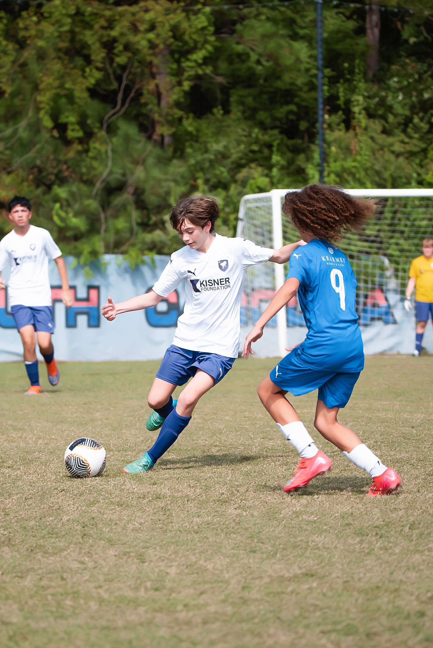 Two soccer players compete for possession of the ball during an intense match on a grassy field.