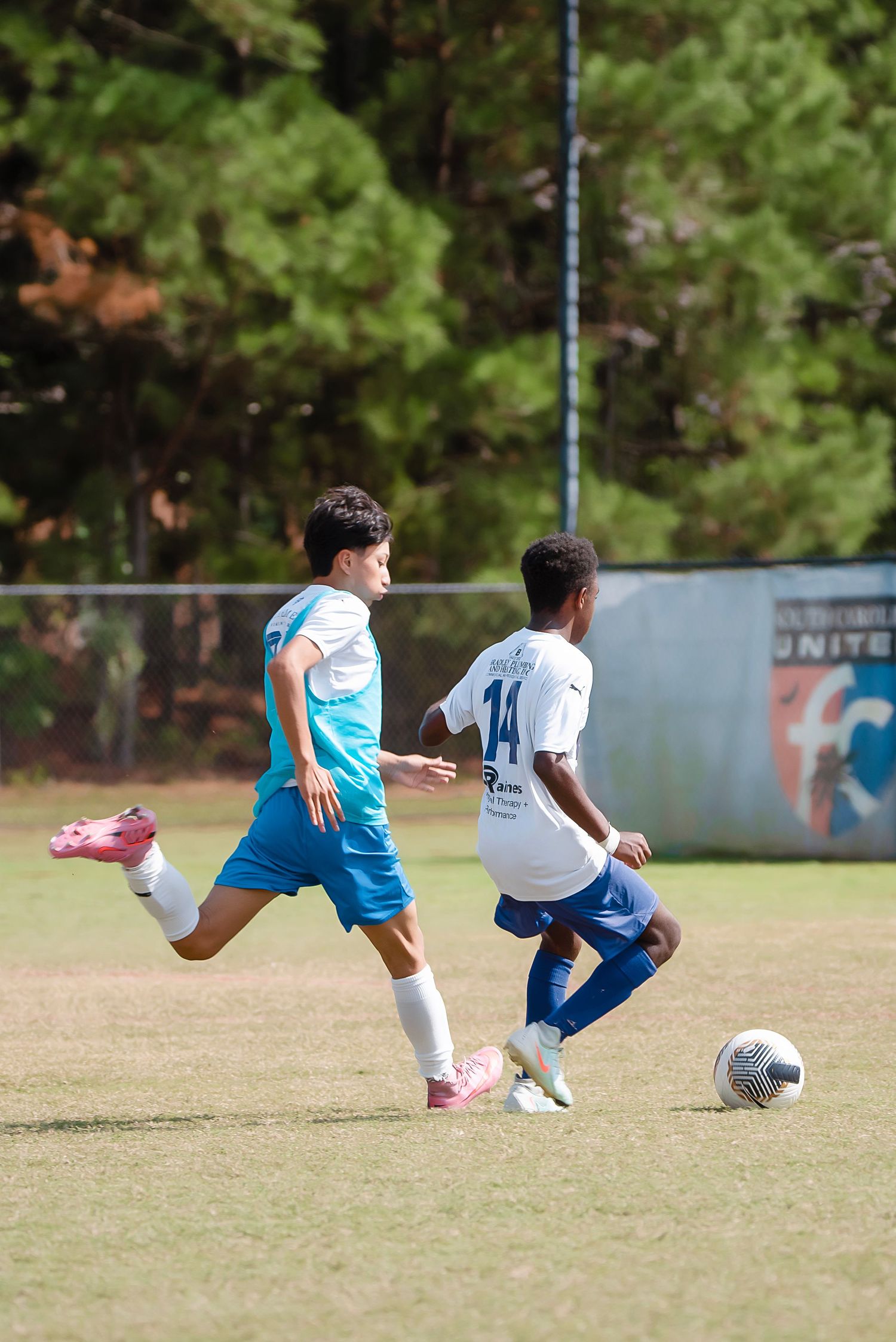 Soccer players dive and slide during an intense practice drill on grass field.